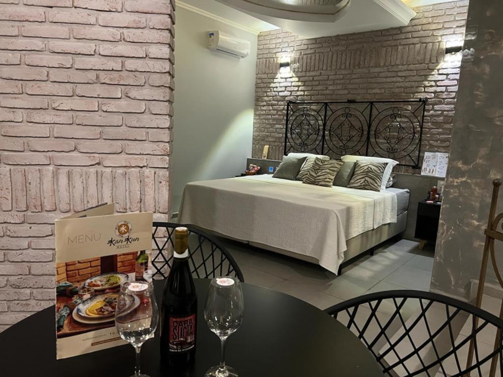 a bedroom with a bed and a table with wine glasses at KANKUN MOTEL SOROCABA -Adult only in Sorocaba