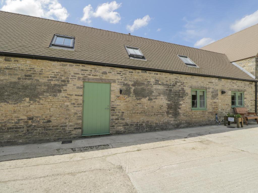 - un bâtiment en briques avec une porte verte dans l'établissement The Old Stable, à Witney