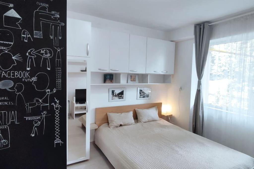 a bedroom with a bed and a wall with drawings on it at Central Park Studio in Cluj-Napoca