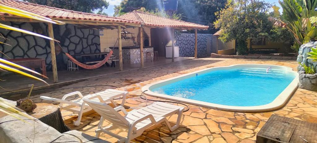 een zwembad met stoelen en een huis bij Rancho Andrade in Três Marias