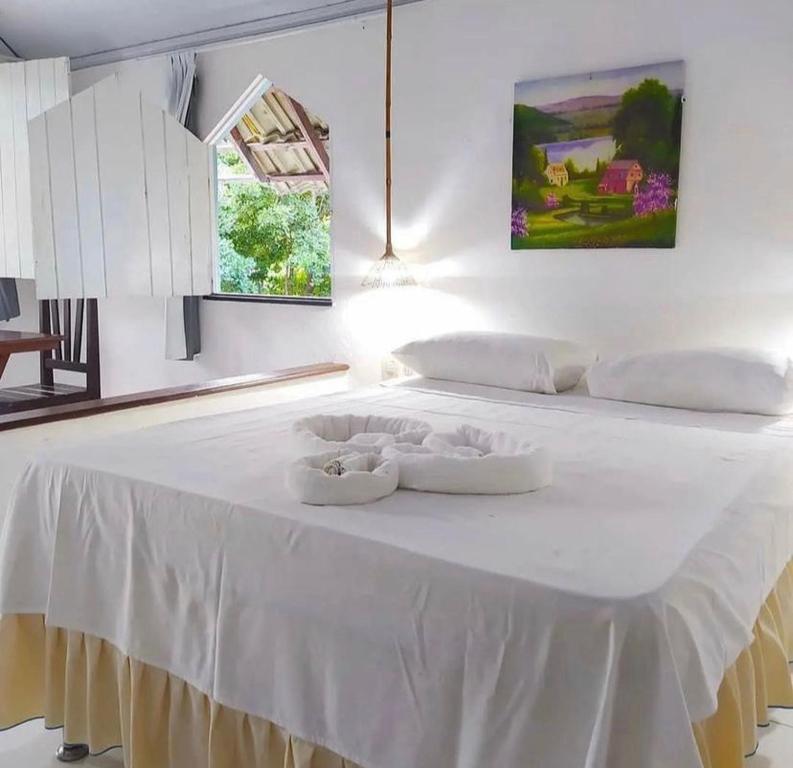 białe łóżko z dwoma białymi naczyniami w obiekcie Pousada Cajibá Imbassaí w mieście Imbassai