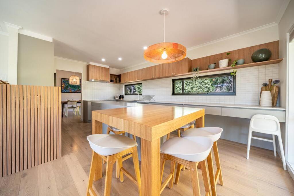 Adelaide Hills Retreat - Surrounded by Nature في Ironbank: مطبخ مع طاولة خشبية وكراسي بيضاء