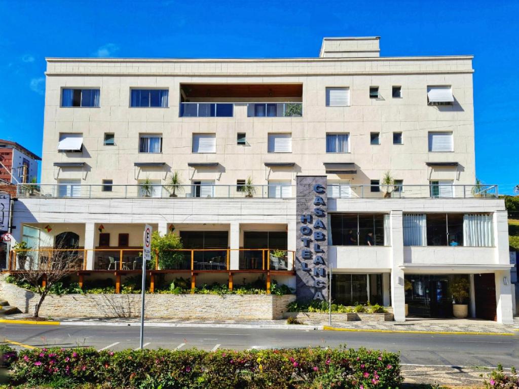 un grand bâtiment blanc sur le côté d'une rue dans l'établissement Hotel CasaBlanca, à Águas de Lindóia