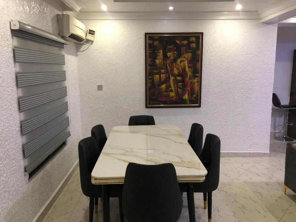 una habitación con una mesa con sillas y una pintura en la pared en SANDS HOMES IKOYI, en Lagos