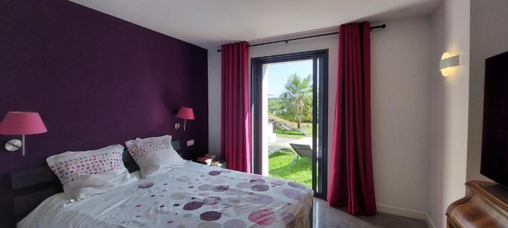 una camera con letto e finestra con tende rosse di FRENCH ART DE VIVRE a Saint-Priest-en-Jarez