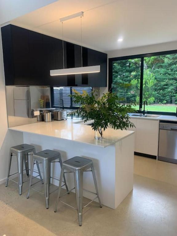 una cocina con un gran mostrador blanco con taburetes en The Architects House Villa 1 2BR, en Hahndorf