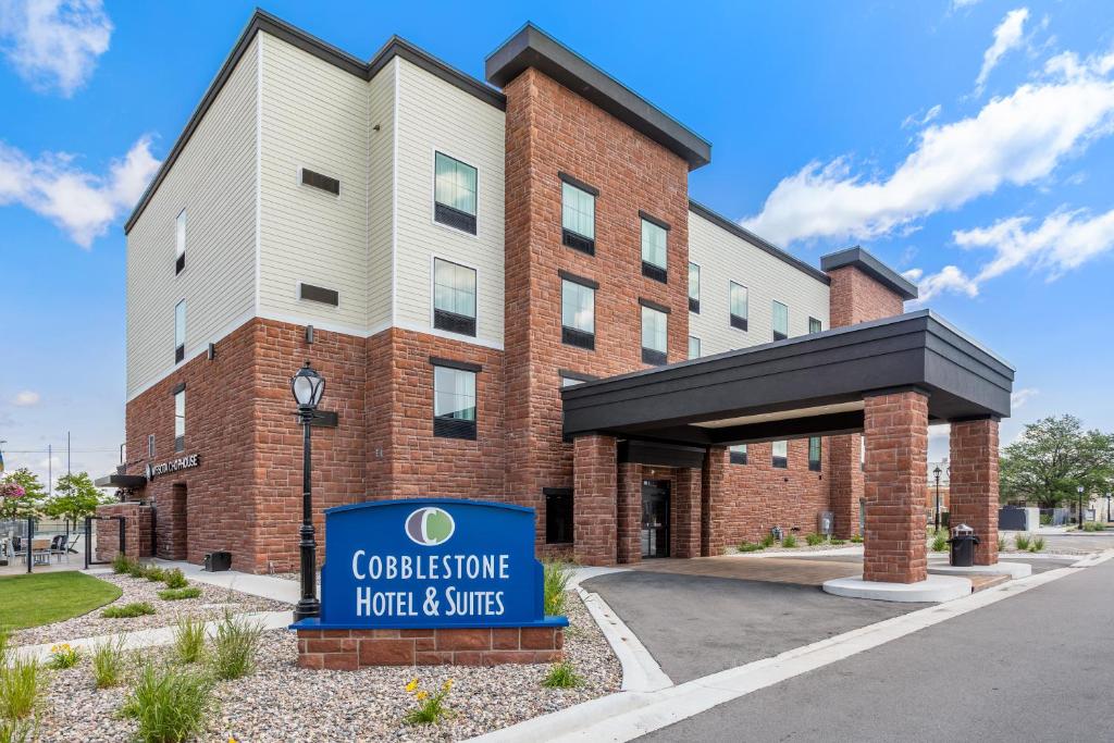 a building with a sign in front of it at Cobblestone Hotel & Suites - De Pere Green Bay in De Pere