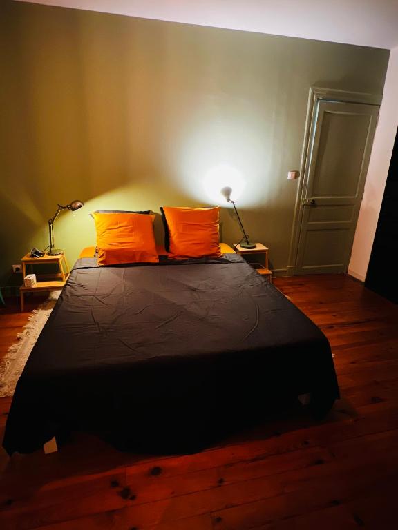 a bedroom with a large bed with two orange pillows at Charmant duplex à BILLÈRE aux portes de Pau in Billère