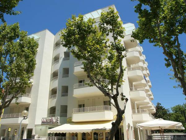 a tall white building with a tree in front of it at Wally Residence in Rimini
