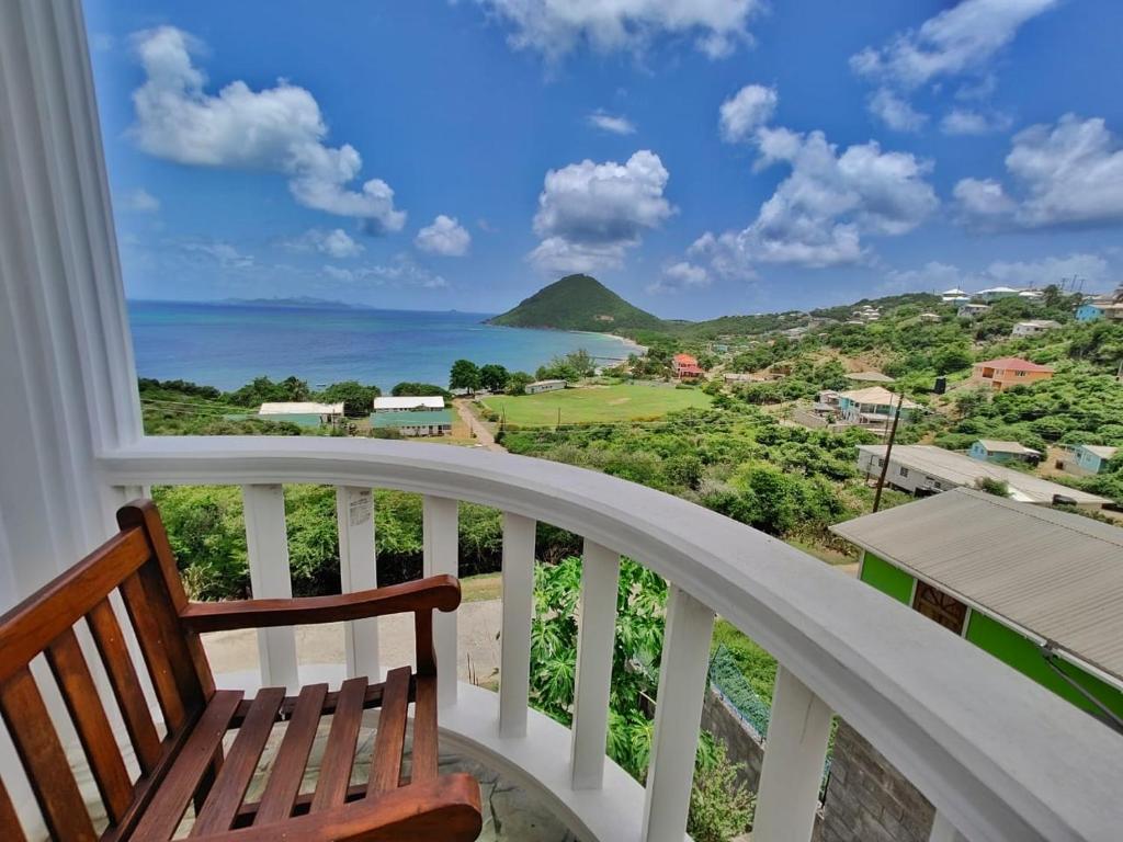 a balcony with a bench and a view of the ocean at Isla Vista Apartment Canouan in Canouan