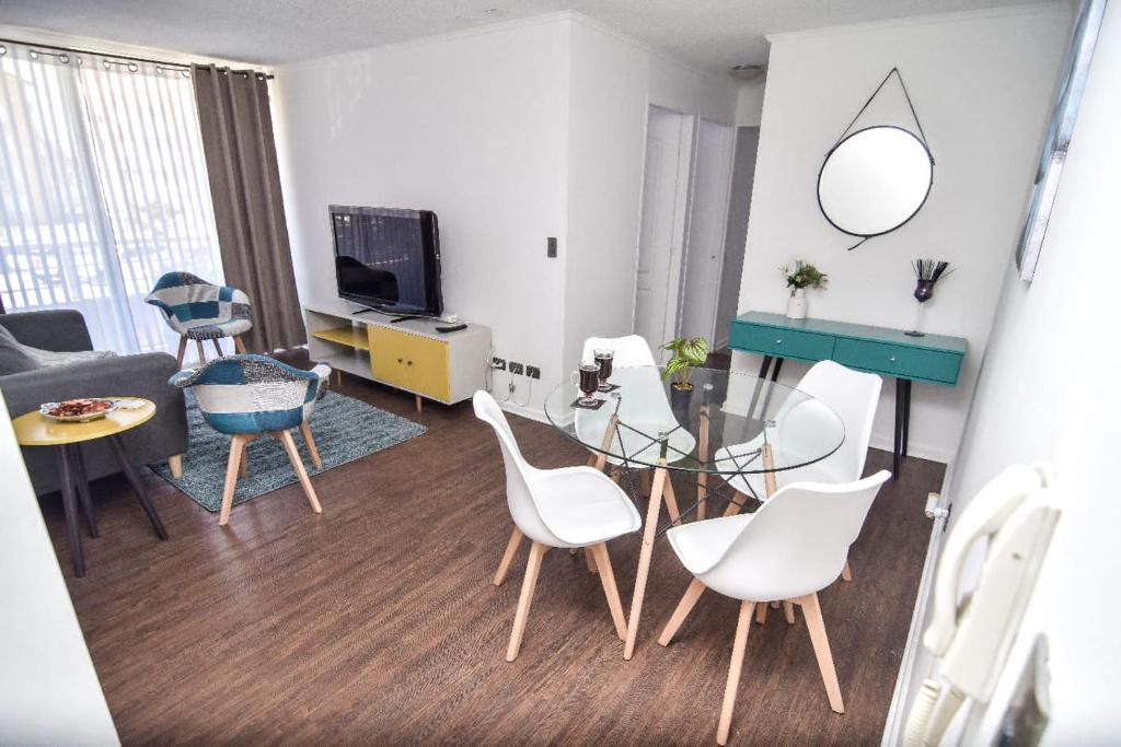 - un salon avec une table en verre et des chaises blanches dans l'établissement Apartamento Altos del boldo, cómodo, à Curicó