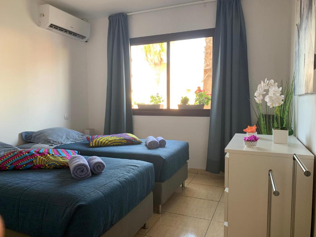 1 dormitorio con 2 camas y una ventana con cortinas azules en Bedroom with shared bathroom and swimming pool en Corralejo