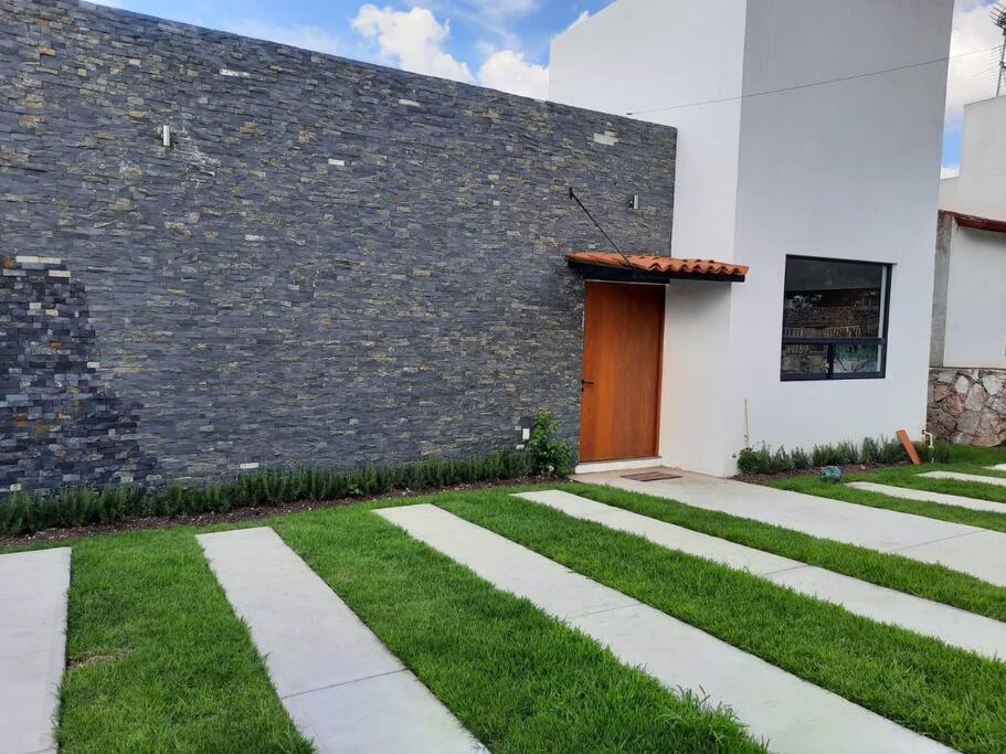a building with a door and a grass yard at Casa GaTo Tequisquiapan in La Tortuga