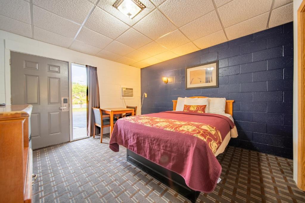 a hotel room with a bed and a table at Sleep-ees Inn, Saginaw & Frankenmuth in Saginaw