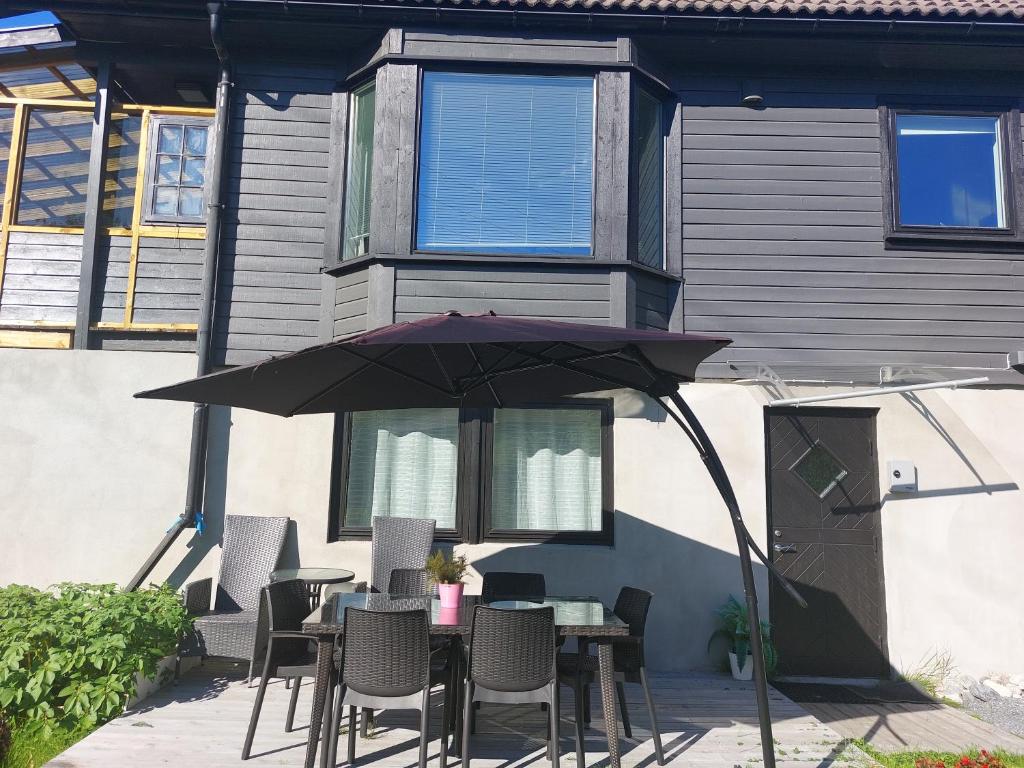 una mesa con sillas y una sombrilla frente a una casa en peaceful place, en Hønefoss