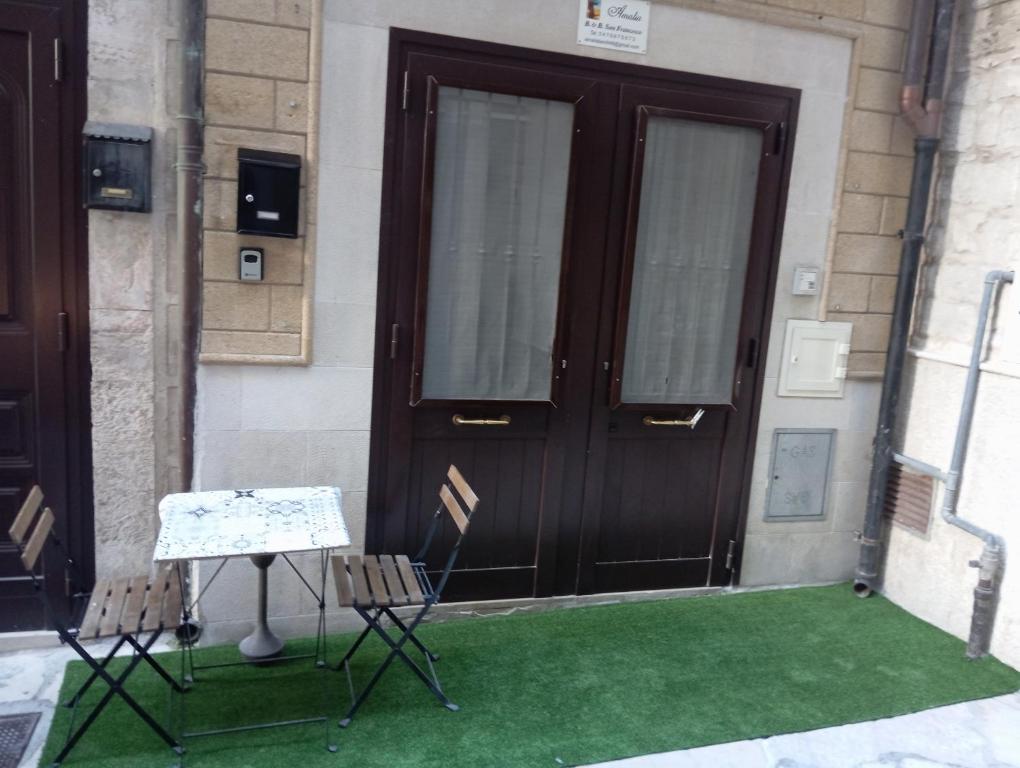 ein Paar Stühle und ein Tisch vor einer Tür in der Unterkunft Amalia B&b San francesco in Bari