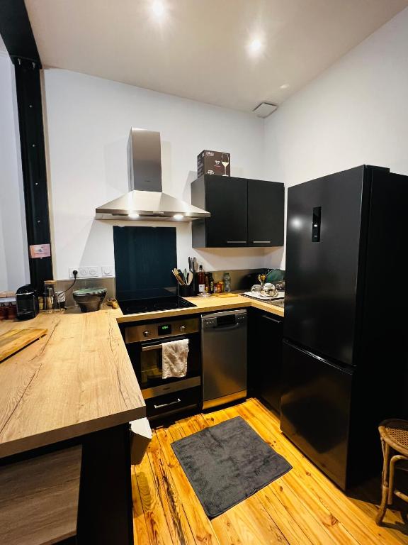 a kitchen with black appliances and a wooden floor at Charmant duplex à BILLÈRE aux portes de Pau in Billère
