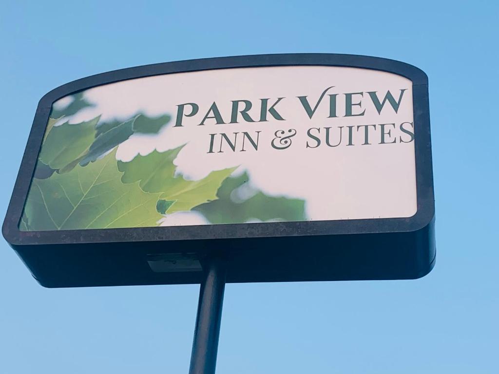una señal de aparcamiento para una posada y suites con vistas al parque en PARK VIEW INN & SUITES en Hoisington