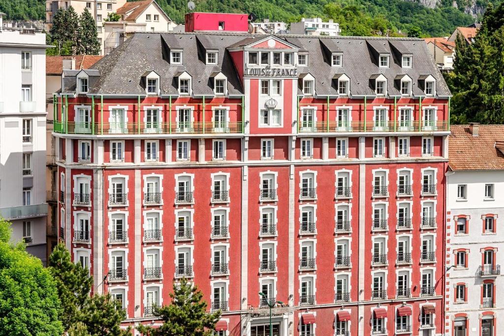 un gran edificio rojo con muchas ventanas en Hôtel Saint Louis de France, en Lourdes