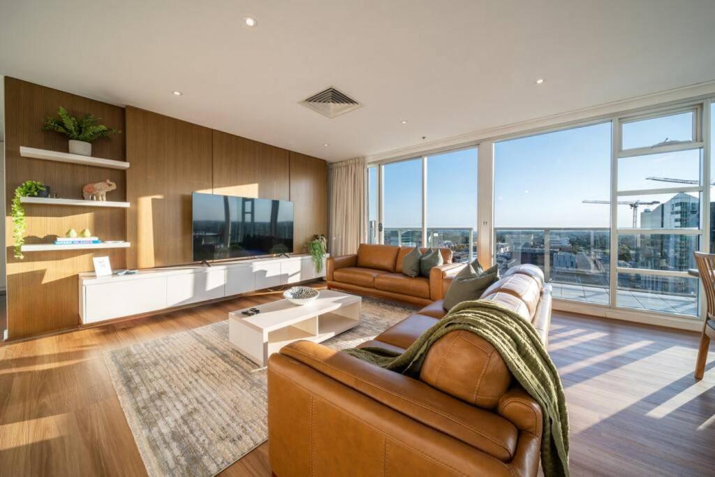 a living room with a couch and a tv at The Views Penthouse - Cityscape & Parkland Scenery in Adelaide