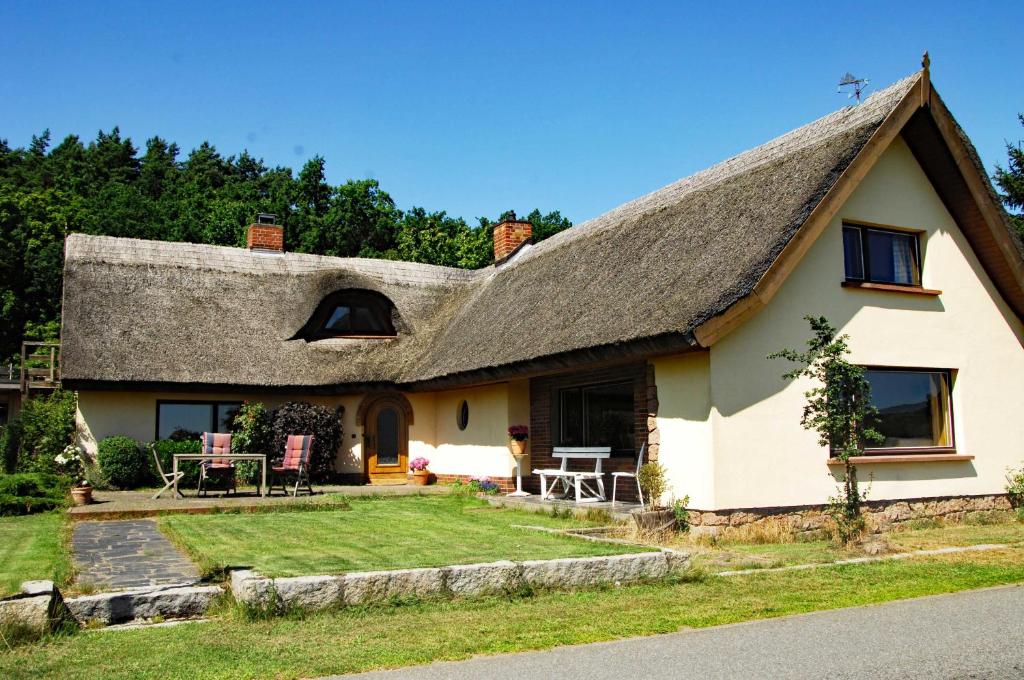 een huisje met een rieten dak en een tuin bij Reeddachhaus mit Seeblick - Ruhe - traumhafter Lage am Selliner See in Ostseebad Sellin
