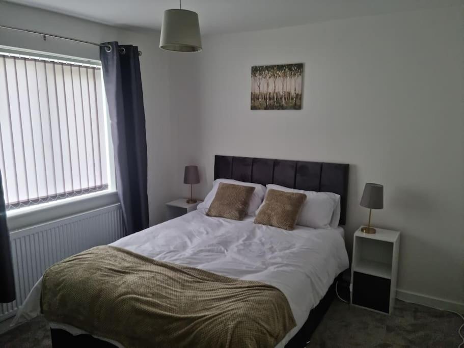 um quarto com uma grande cama branca e 2 almofadas em 5 bedroom house - Cheshire Oaks em Ellesmere Port