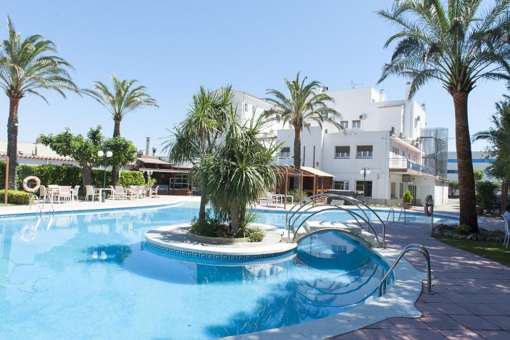 a swimming pool with palm trees in a resort at Ampuria Inn in Empuriabrava