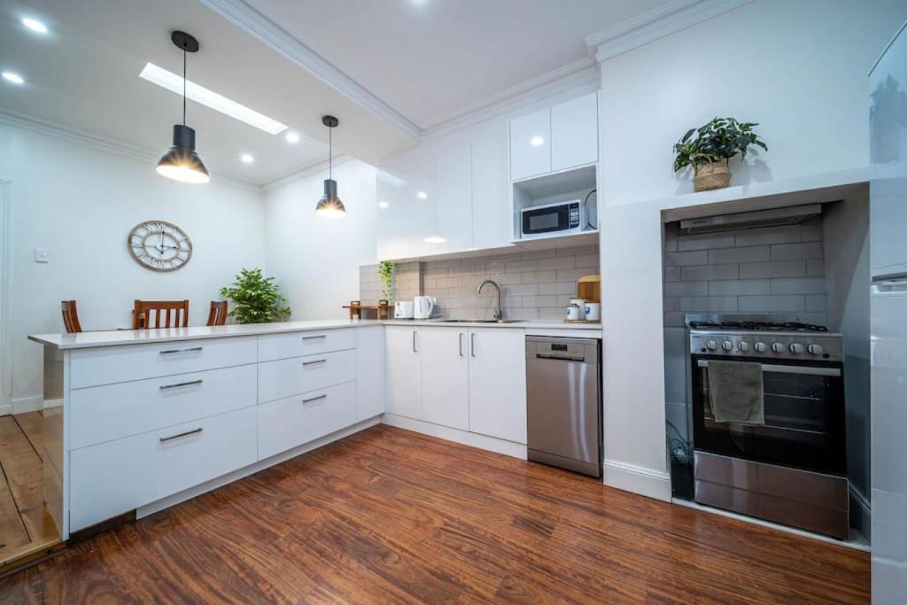 a kitchen with white cabinets and a stove top oven at Plane Tree Cottage North Adelaide in Bowden