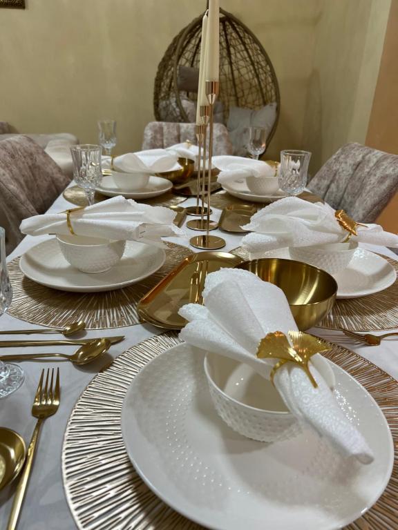 une table avec des assiettes blanches et des ustensiles en or dans l'établissement Magnifique appartement a la marina d agadir, à Agadir