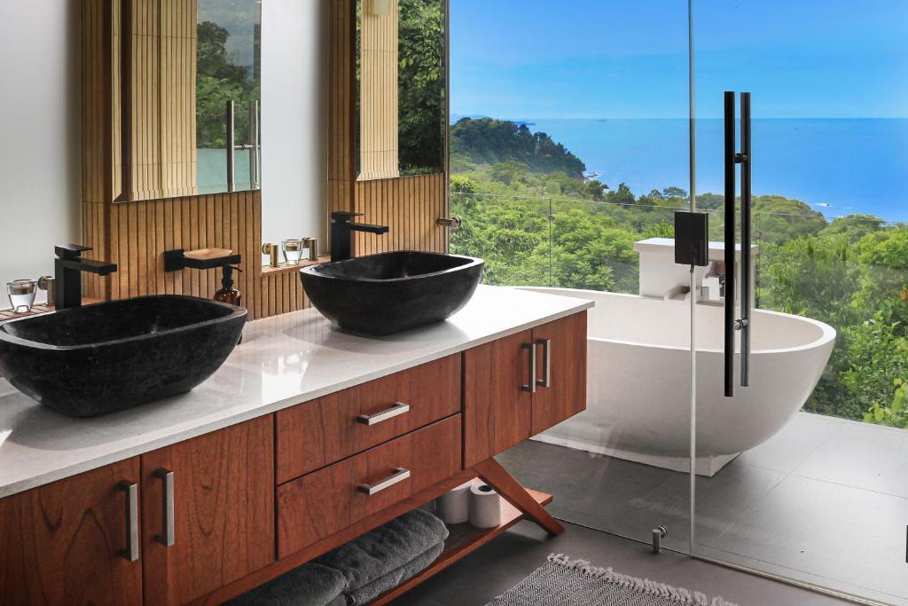 two sinks in a bathroom with a large window at Casa Sulit in Dominical