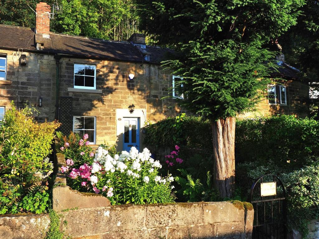 a stone house with flowers in front of it at Rose Cottage in Matlock