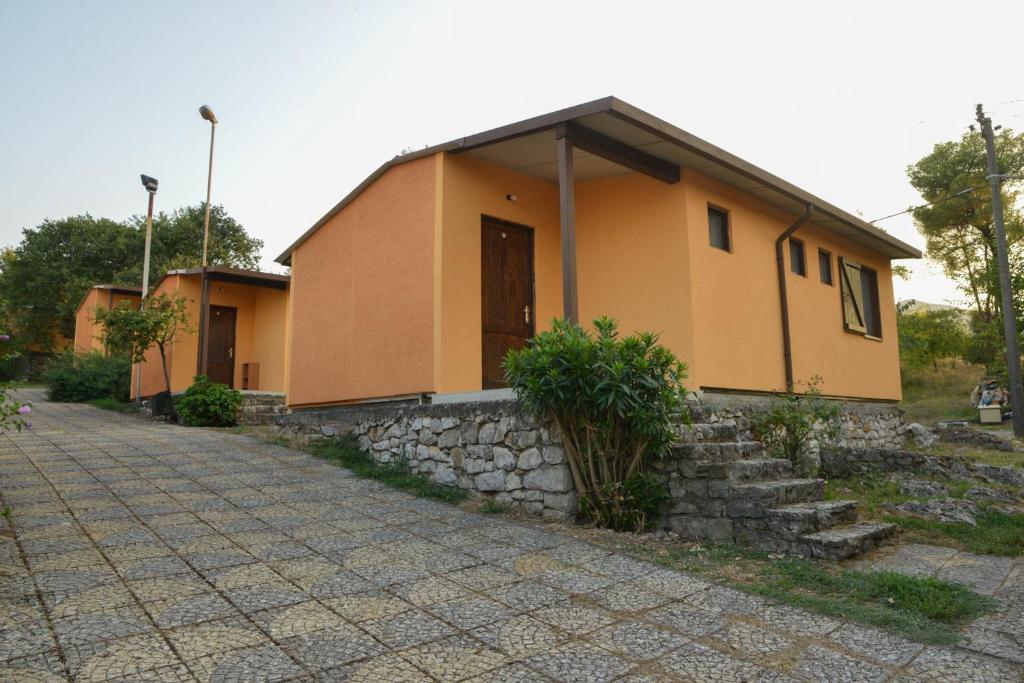 una pequeña casa amarilla con una pared de piedra en Village of Peace - House 25, en Shkodër
