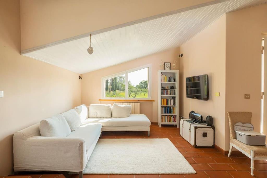 uma sala de estar com um sofá branco e uma televisão em La Gipsofila Attic em Osimo
