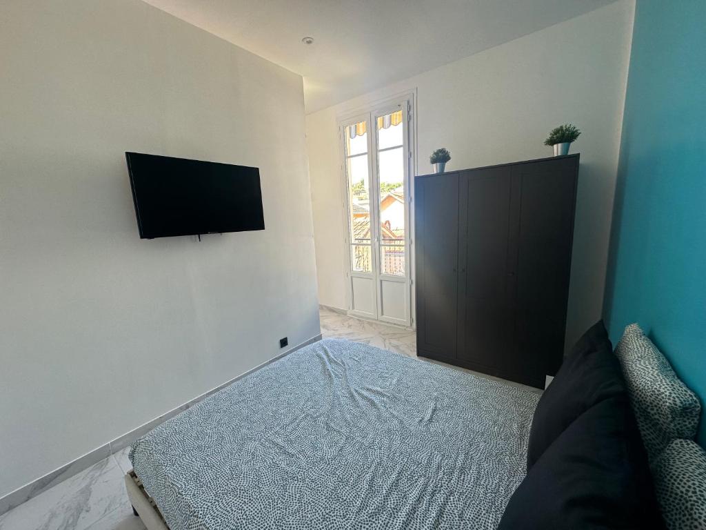 a bedroom with a bed and a television on a wall at La maison de Giulia Menton in Menton