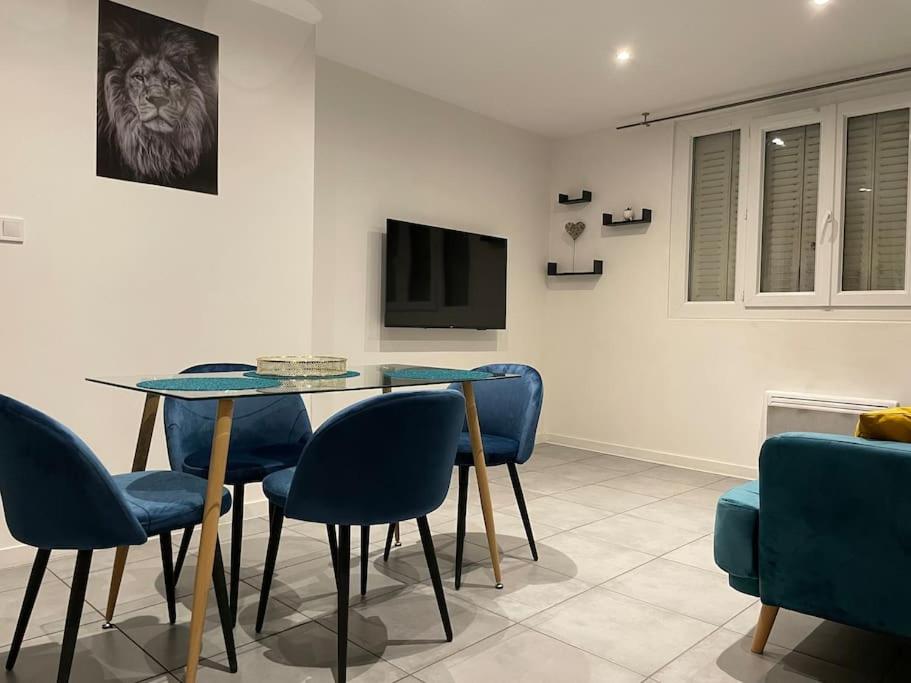 a dining room with a glass table and blue chairs at Logement Rénové - Une Expérience Unique - Wifi Gratuit in Grenoble