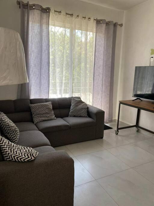 - un salon avec un canapé et une télévision dans l'établissement Amplio departamento con alberca, à Playa del Carmen