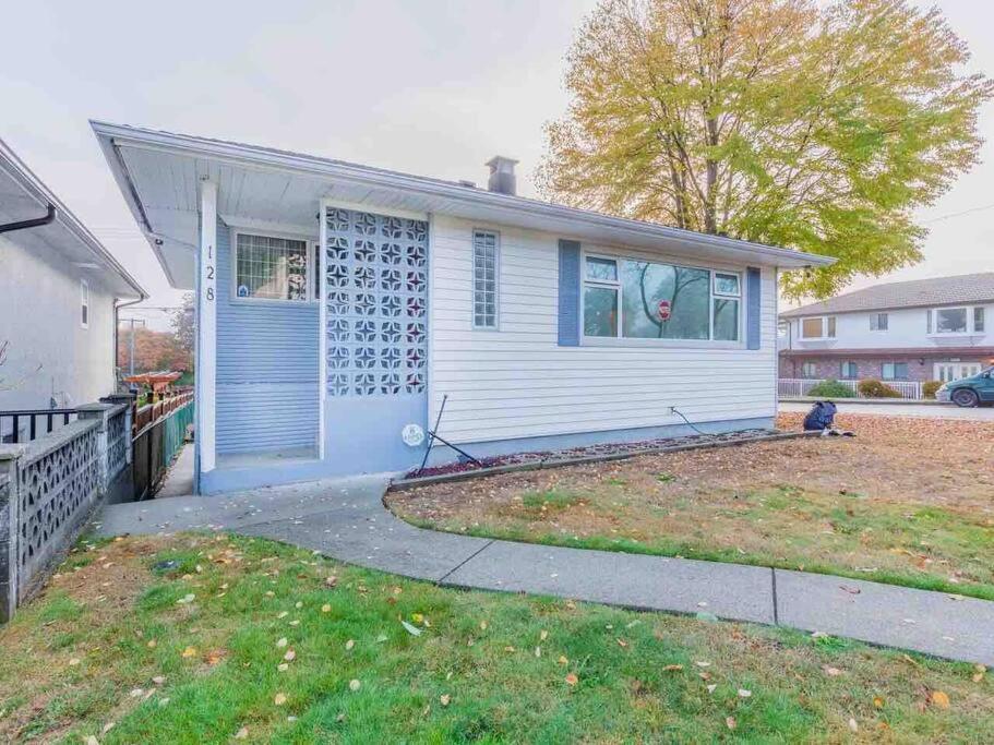 een wit huis met een blauwe deur en een tuin bij Cozy Capitol Hill Bungalow - 3BD/2BA Retreat in Burnaby