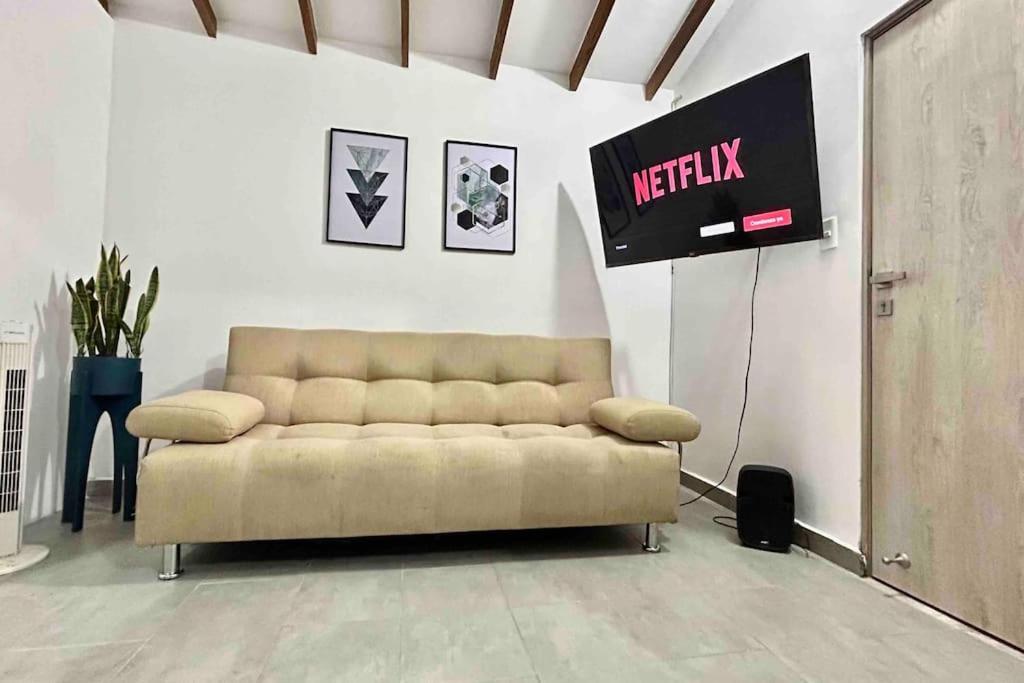 a couch in a living room with a sign on the wall at Stefi house en Belén la mota Wifi in Medellín