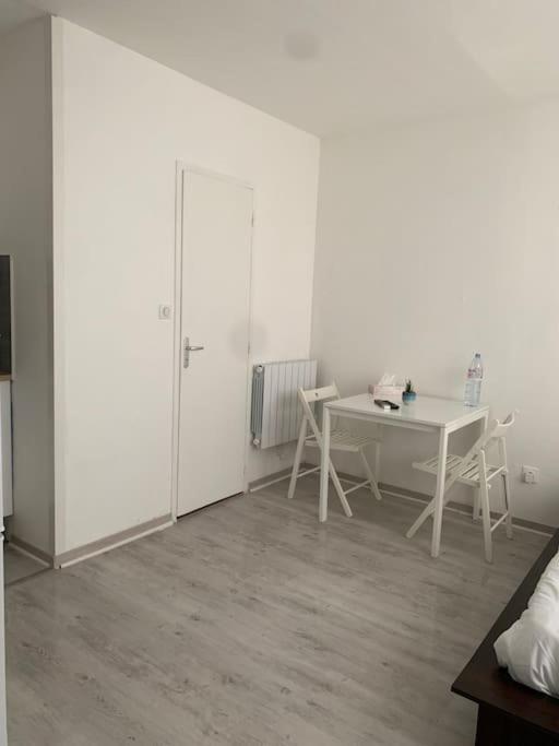 Cette chambre blanche dispose d'une table et de chaises blanches. dans l'établissement Studio en plein centre ville, à Quimper