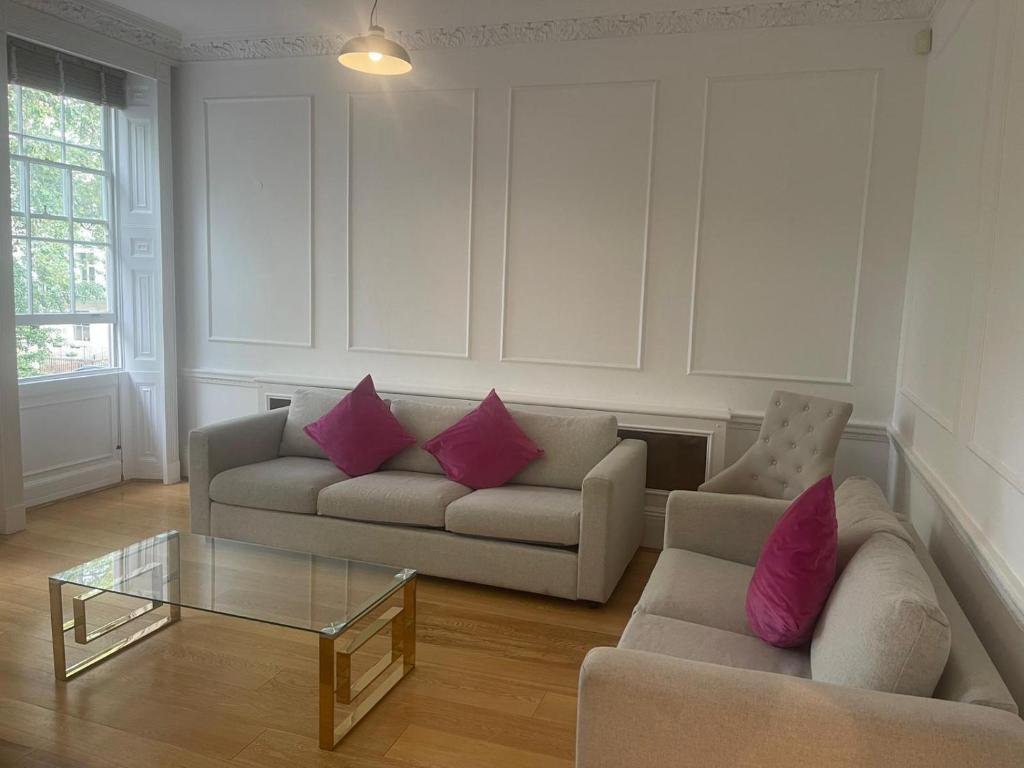 a living room with two couches and a glass table at Kensington Luxury Apartments in London