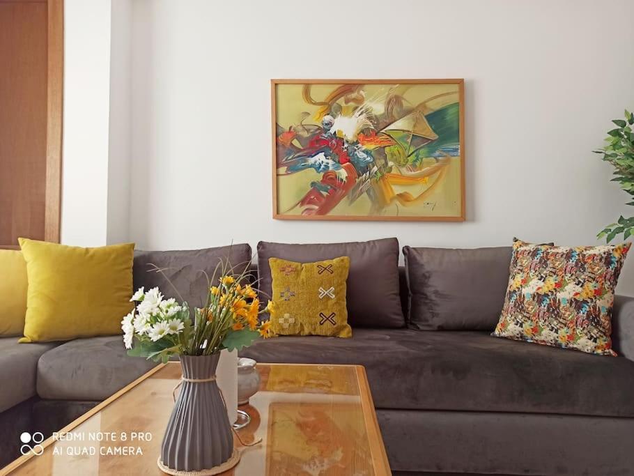 a living room with a couch and a table with flowers at Hamza Boho Oasis in Essaouira