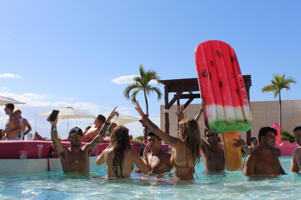 un grupo de personas en una piscina con una tabla de surf en Hotel The Palm en Playa del Carmen