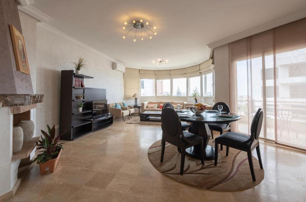 a living room with a table and chairs and a couch at APARTMENT HAY RYAD 200 M2 STANDIG in Rabat