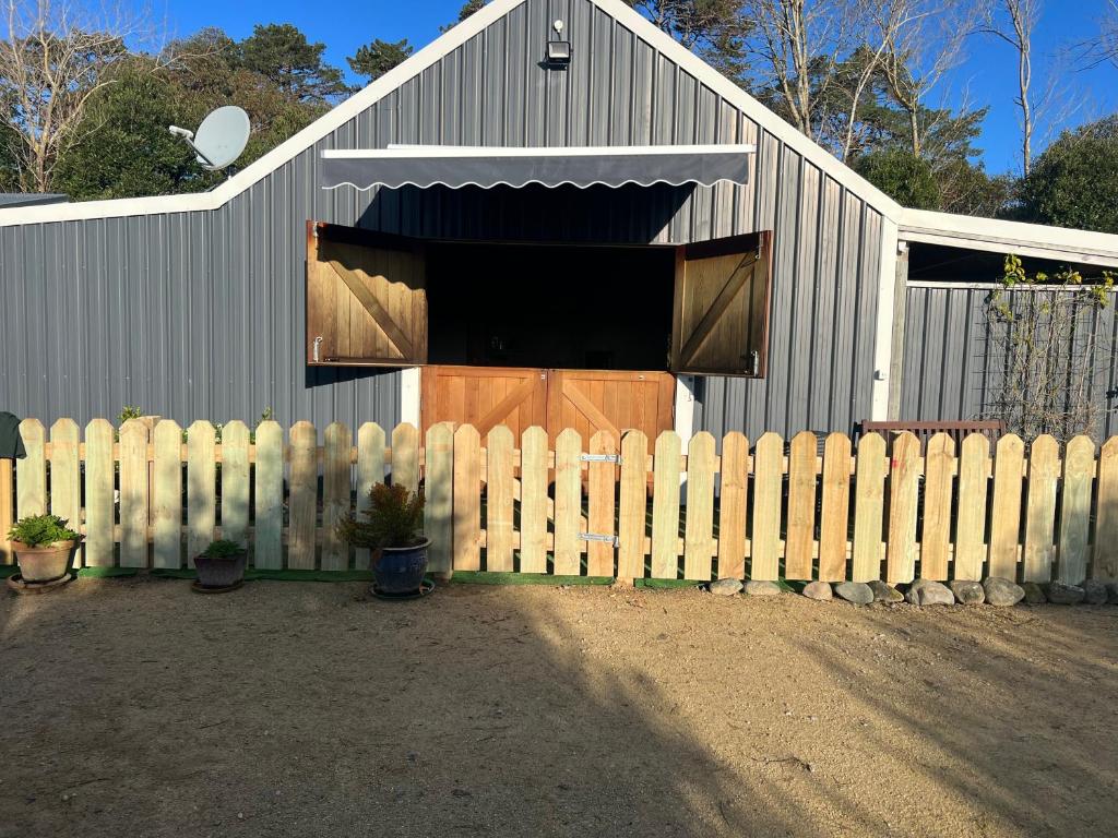 une grange avec une clôture devant elle dans l'établissement Waiora la grange cottage, à Otaki