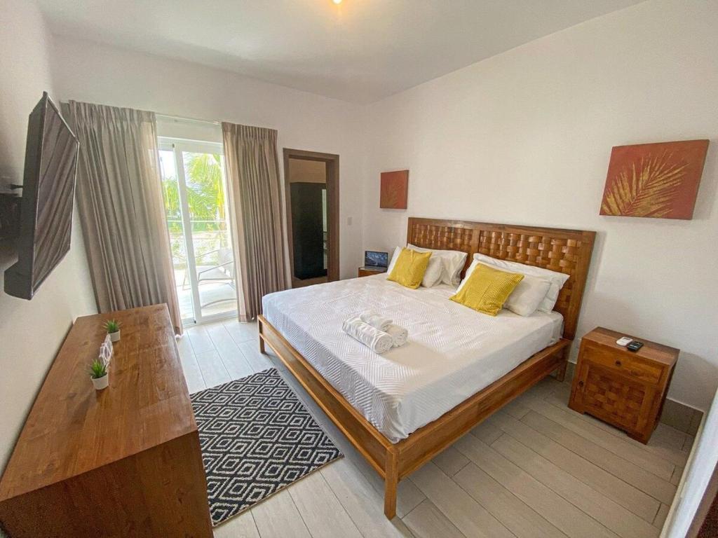 Un dormitorio con una cama con almohadas amarillas y una mesa. en Acceso a la playa 2 hab 3 camas 6 pax bella piscin, en Punta Cana
