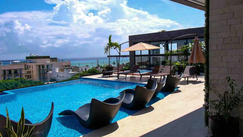 a swimming pool with chairs and a view of the ocean at Stayon5a Av penthouse with PrivatePool in Playa del Carmen