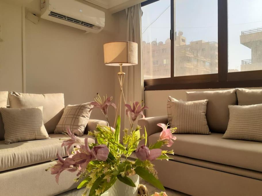 a living room with a couch and a vase with flowers at Bright and spacious 2bdr apt للعائلات Nasr city heart in Cairo