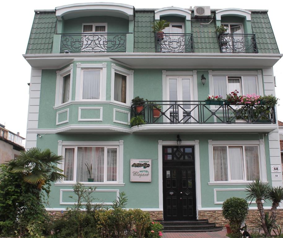 - un bâtiment vert avec des balcons et des fleurs dans l'établissement Hotel Elegant Garden, à Batoumi