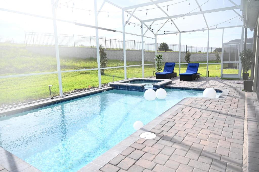 a swimming pool with two blue chairs and anophe at Luxurious 8-Room Oasis near Disney in Kissimmee