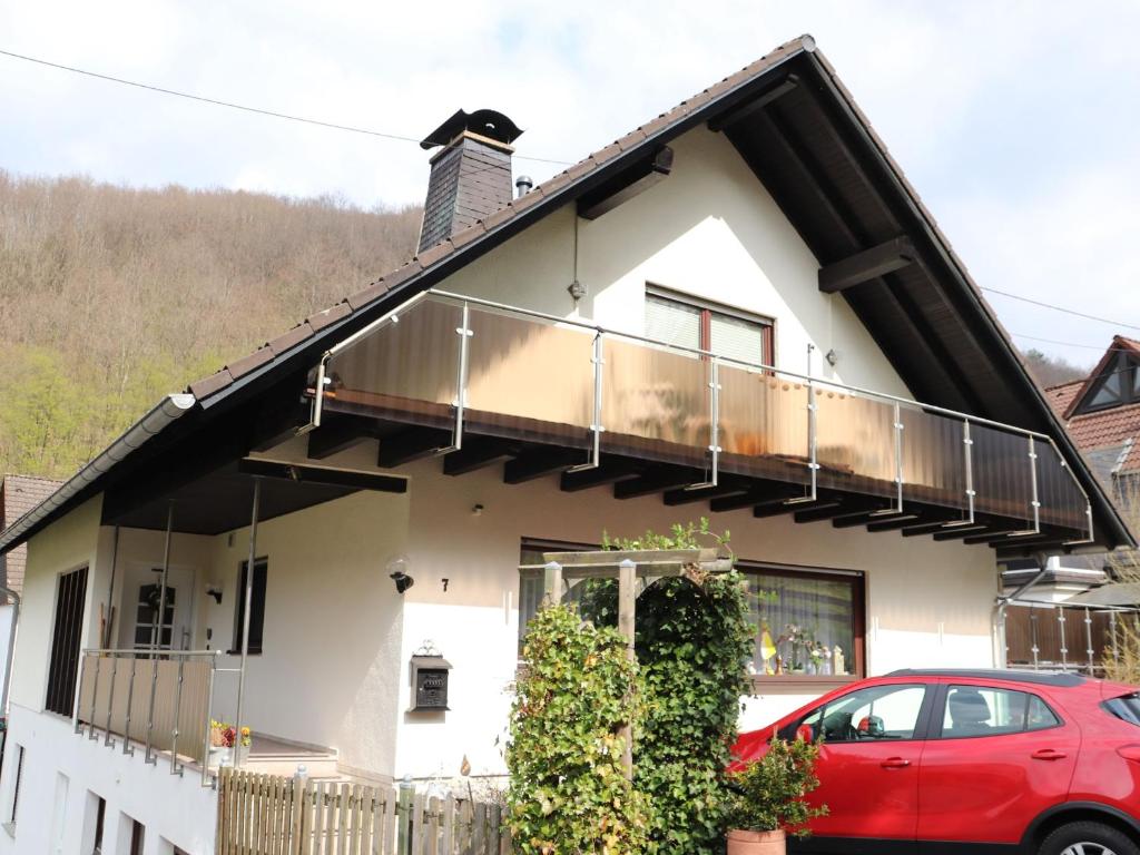 a house with a balcony and a red car at Fewo-rosenberger-sauerland in Lennestadt